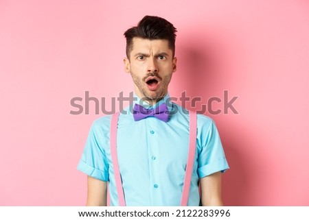 Shocked and offended young man frowning, looking at someone rude, standing insulted on pink background Royalty-Free Stock Photo #2122283996