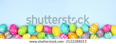 Colorful Easter Egg bottom border over a pastel blue paper banner background. Copy space. Royalty-Free Stock Photo #2122288013