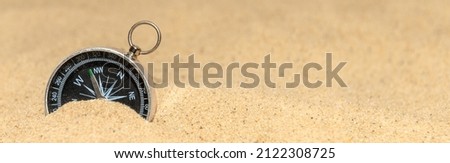Compass on the sand at the beach. Concept of travel or direction. Banner design