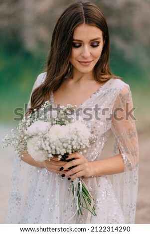 Portrait of bride with bouquet. Young beautiful bride holds wedding bouquet in her hands. Royalty-Free Stock Photo #2122314290