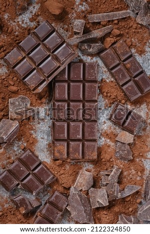 Background Of Chocolate Pieces. Chipped Dark Chocolate Pattern.  Composition of bars and pieces of different dark chocolate, grated cocoa. Top View