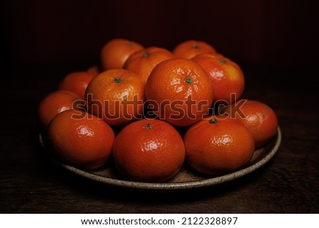 Many mandarin oranges on plate and wooden table