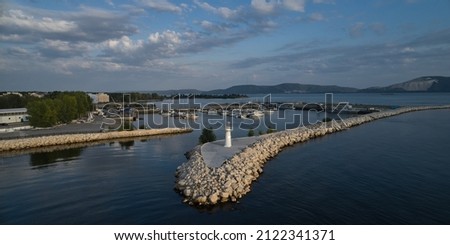 Aerial view of the harbor and yacht club. Lighthouse at the entrance to the harbor. Volga river. Mountains are visible in the distance. Summer evening.