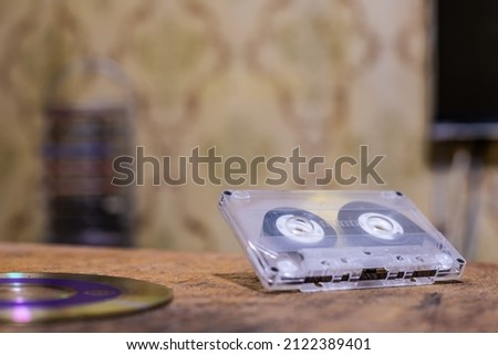 Audio cassette and CD on a blurry background of retro wallpaper. Nostalgia for the nineties.Background photo.A photo on the desktop.