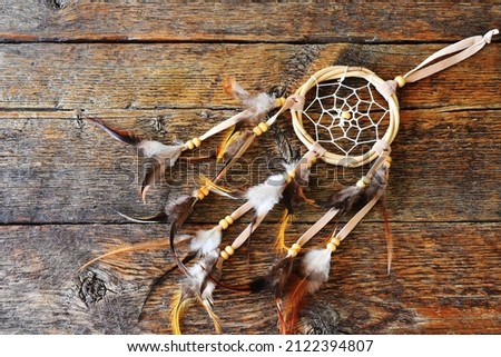 A top view image of a brown and yellow dreamcatcher on a dark wooden table top. 