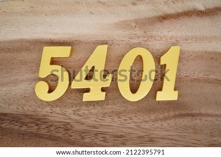 Wooden Arabic numerals 5401 painted in gold on a dark brown and white patterned plank background.
