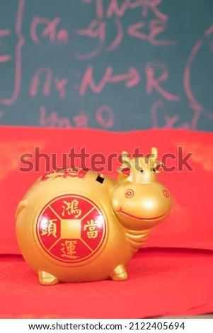 Taurus piggy bank on red background.The Chinese characters in the picture mean: "to attract wealth and treasure"