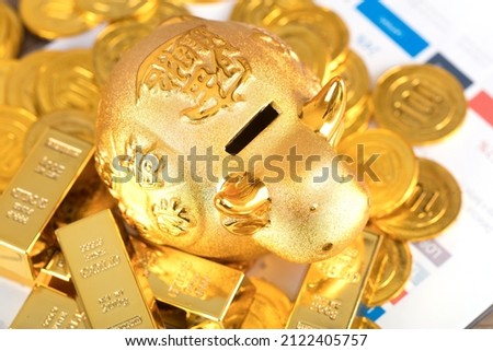 Golden calf piggy bank on gold coins and bars.The Chinese characters in the picture mean: "to attract wealth and treasure"