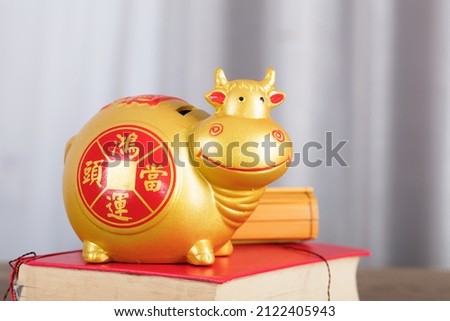 Taurus piggy bank on a book.The Chinese characters in the picture mean: "to attract wealth and treasure"