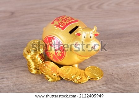 Taurus piggy bank and a pile of gold coins.The Chinese characters in the picture mean: "to attract wealth and treasure"