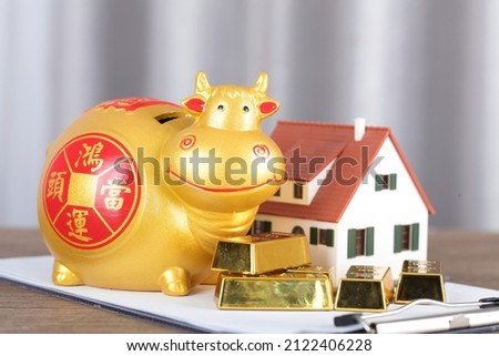 Taurus piggy bank and gold bars next to the house model.The Chinese characters in the picture mean: "Lucky Strike"