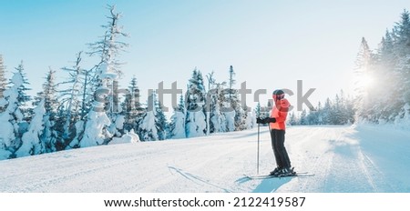 Skiing woman skier looking at mountains landscape nature outdoors standing holding skis. Alpine ski riding white powder snow slopes in cold weather on idyllic view banner. Winter sports in Canada.