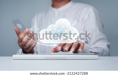 Cloud storage icon with businessman working with computer and glass phone. Cloud computing, technology, service, and connectivity concepts. Data protection, exchange, file, and information transfer.