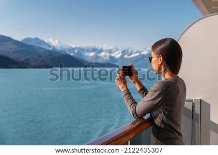 Alaska cruise ship passenger photographing amazing landscape entering Glacier Bay National Park, USA. Woman tourist taking photo picture using mobile cell smart phone on travel vacation.