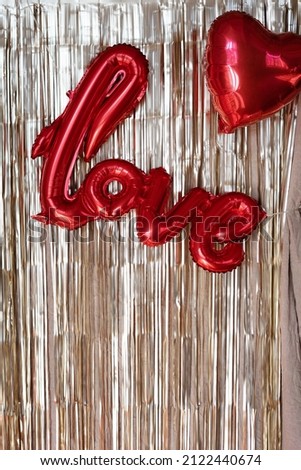 Valentine's day photo zone with tear drop curtain and balloons. Red hearts and the word love on a golden background.