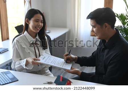 Happy young asian man signing rental contract with real estate broker.
