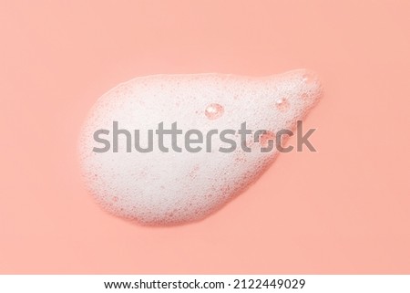 Skincare cleanser foam texture. Soap, shampoo, cleansing mousse bubbles swatch on pink color background. Face wash lather closeup