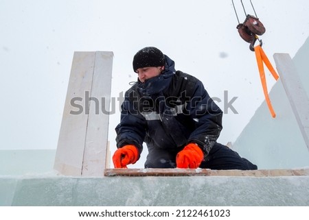 The builder cleans the ice panel with a wire brush from snow