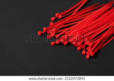 Colored, bright, red, plastic cable ties on a black background. place for the inscription. Royalty-Free Stock Photo #2122472843