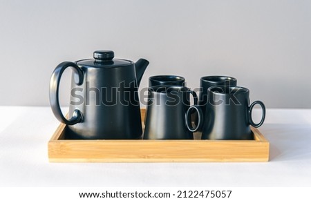Teapot and cups, a set of dishes for tea drinking in a wooden tray.