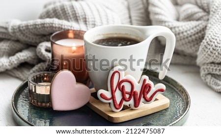 A cozy still life for Valentine's Day with a cup, decor details and gingerbread.