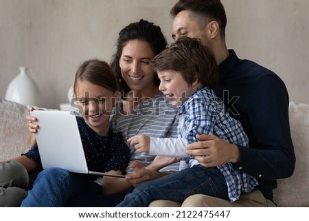 Happy joyful children and parents watching movie on laptop, resting on couch, shopping on internet, booking hotel online, using internet app, virtual application on computer for family shopping