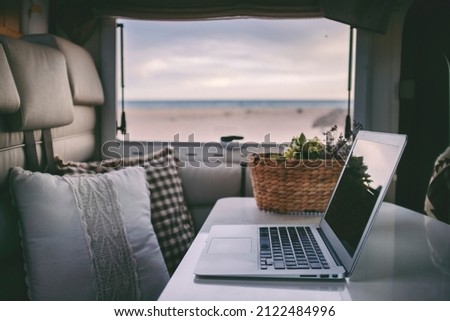 Remote onilne work and smart working travel concept with laptop computer inside a van camper interior with beach view. Freedom from office modern lifestyle for alternative life and people Royalty-Free Stock Photo #2122484996