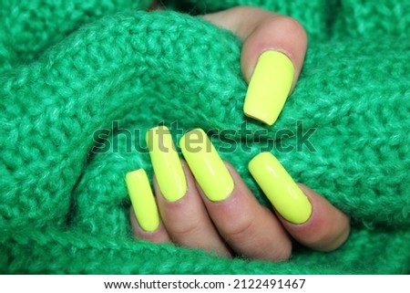 Stylish trendy female manicure. Neon yellow nails on green  background. Nail polish. Art manicure. Modern style.