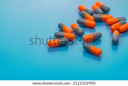 Orange-gray antibiotic capsule pills on blue background. Antibiotic drug resistance. Pharmaceutical industry. Prescription drug. Capsule pills production manufacturing. Pharmacology and toxicology. Royalty-Free Stock Photo #2122502900