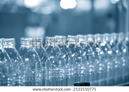 The empty PET bottles  on the conveyor belt for filling process in the drinking water factory. The hi-technology of plastic bottle manufacturing process. Royalty-Free Stock Photo #2122510775