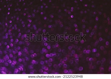 Bokeh light background. Blur neon circles. Fluorescent sparkles. Defocused purple pink color glowing round specks texture on dark abstract overlay.