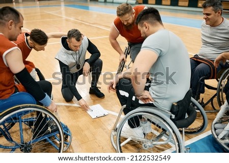 Basketball coach and his team with disabilities discussing about game strategy during sports training.  Royalty-Free Stock Photo #2122532549