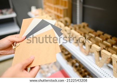 Male hand choosing recycled paper swatch in stationery shop. Paper material selection for design element