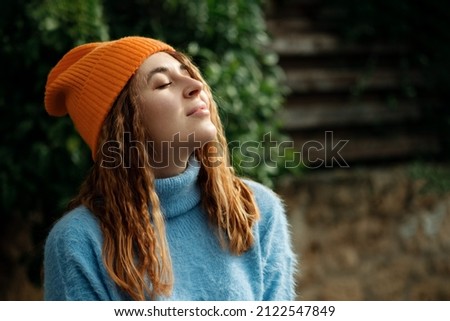 Sensitivity to nature concept.Allow your mind and body to unwind.Portrait carefree beautiful happy woman traveler,girl wearing cozy sweater and knitted orange hat, clothing autumn season. Royalty-Free Stock Photo #2122547849