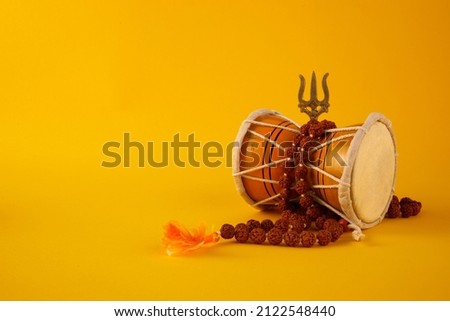 Shivaratri background with Shivas trident and Pellet Drum Damroo musical instrument . Hindu festival Maha Shivratri Royalty-Free Stock Photo #2122548440