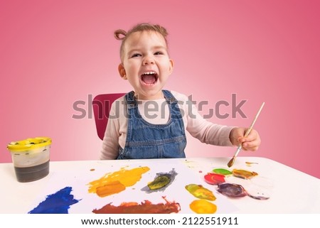 a girl draws and laughs on a pink background