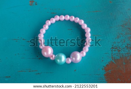 pink pearl bracelet accessories for girls. Abstract blue painted wooden table background.