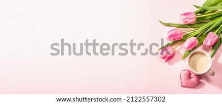 Romantic flat lay composition with a cup of coffee, soft felt hearts, and fresh tulips. Valentines or Mother's Day, Wedding, good morning concept. White wooden background, banner format