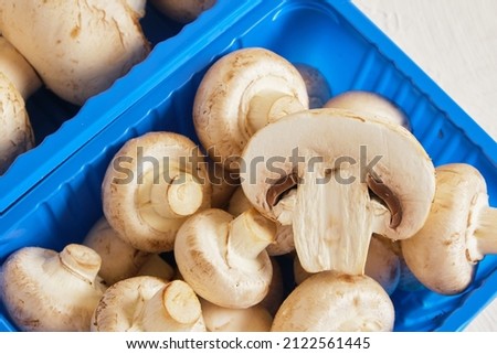 Fresh champignons in plastic packaging close up top view