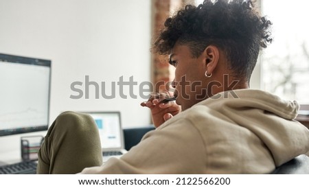Thoughtful african american broker analyzing stock graph on pc screens and vaping. Working distantly. Stock exchange trader working distanly. Focused exhausted businessman work on own project.