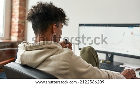 African american trader investor vaping electronic device while working on pc. Young male businessman working from home office. Analyzing data concept. Graphs and reports of stock market trading.