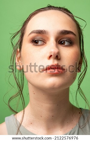 Young woman with gathered dark hair with brown eyes isolated on green portrait