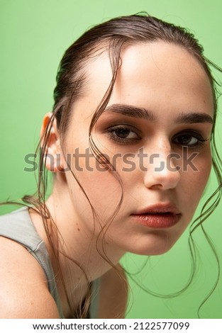 Young woman with gathered dark hair isolated on green portrait