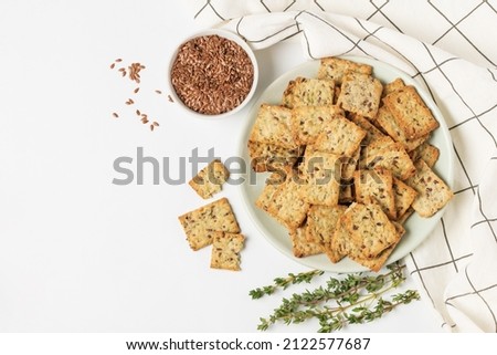 Square diet cookies with thyme, flax seeds and spices  in a light plate on white background. Crunchy herbal crackers top view with copy space Royalty-Free Stock Photo #2122577687