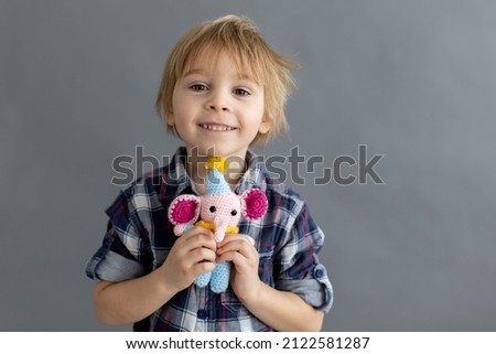 Little toddler child, blond boy, playing with handmade little stuffed knitted toy