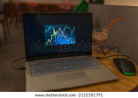 Laptop screen with stock charts. Work on a computer in a cafe. Freelancing in a coffee shop. Trading, cryptocurrency. High quality photo