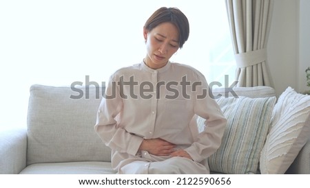 Asian female complaining of abdominal pain Royalty-Free Stock Photo #2122590656