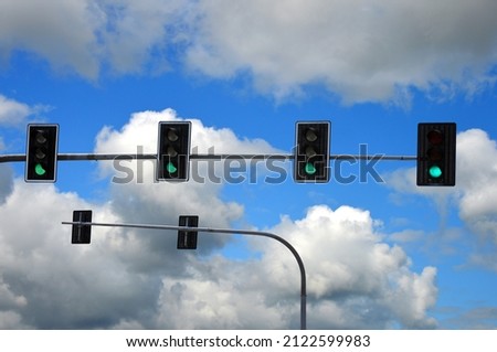 Green road lights on a background of the sky with clouds