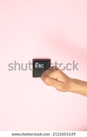 Hand prepares to hit the Esc button on pink background. Escape from dept, love, bad situation, relationship etc. Flat lay.