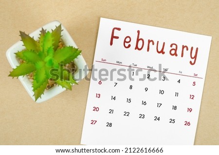 The February 2022 calendar with plant pot on brown paper background.
